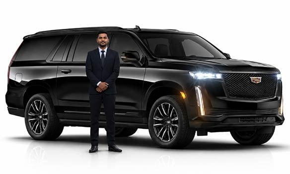 Professional chauffeur standing beside black Cadillac Escalade luxury SUV